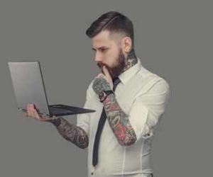 Man with lots of tattoos holding laptop