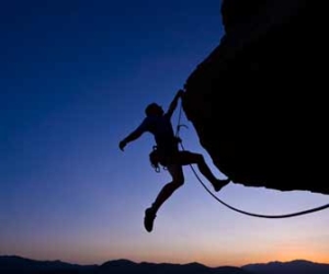 Silhouette or rock climber making challenging climbing move image