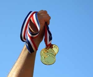 Olympic Athlete holding multiple medals in the air