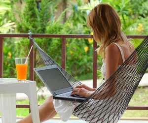 Woman in hammock chair working remotely on computer