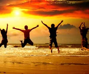 Group of friends jump into the air on the beach while the sunsets