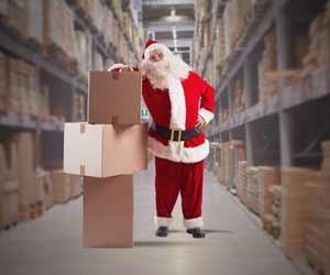 Santa Claus stands next to boxes in warehouse full of items