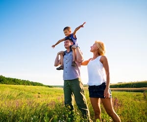 Working parents having fun with child in field on sunny day