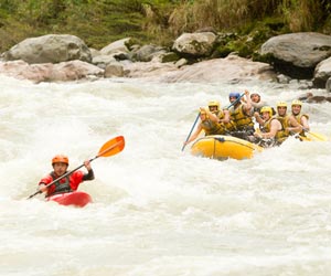 Whitewater rafting with kayaker and raft on wild river