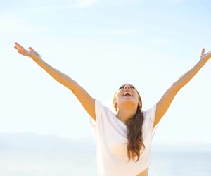 Happy woman rejoicing outside with arms out stretched