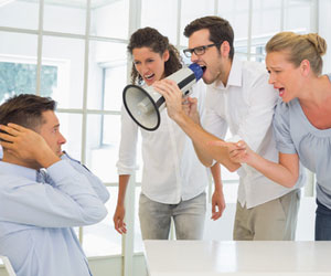 Three workplace bullies yelling at co-worker through megaphone while at work