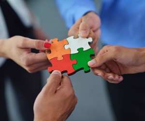 Four business people hold interlocking puzzle pieces