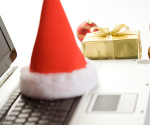 Santa hat sitting on laptop with wrapped present in background