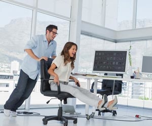 Two employees racing chairs around a cool office